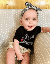 Baby girl is wearing a top knot headband featuring a chevron print from By Bella Boutique.